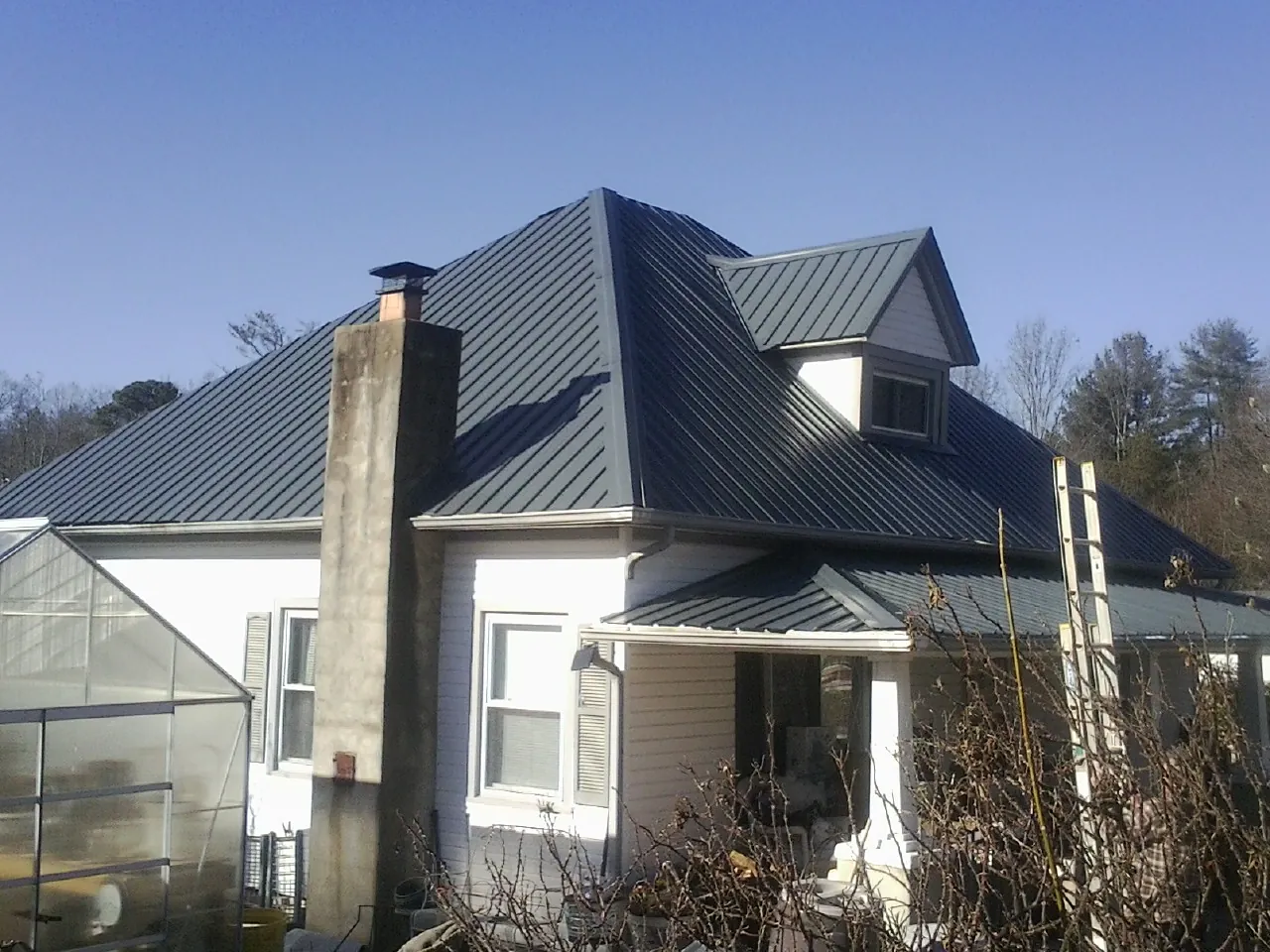 Dark blue standing seam metal roof on a white farmhouse with dormer — Slate & Tile Roof Repair by Roofing Brothers in Aguanga