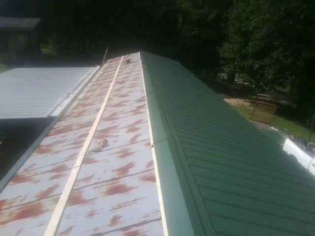 Old rusted panels beside newly installed green metal roofing — Wind Damage Roof Repair by Roofing Brothers in Aguanga