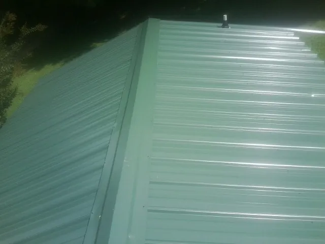 New green metal panels meeting at the ridge of a roof — Flat Roof Repair work by our crew in Aguanga