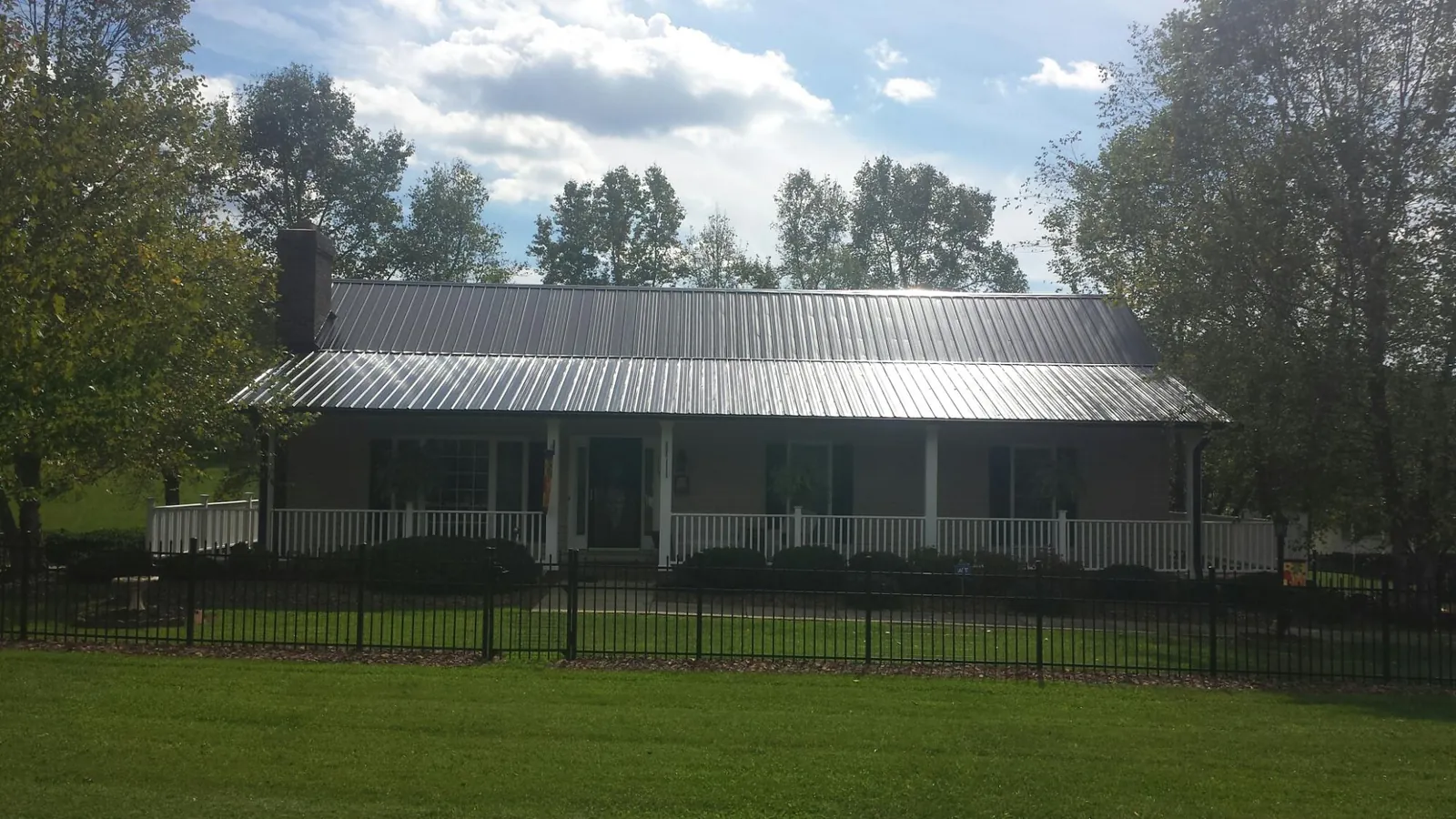 Gray metal roof on a brick ranch with a full width front porch — Gutter Guard Installation work by our crew in Aguanga