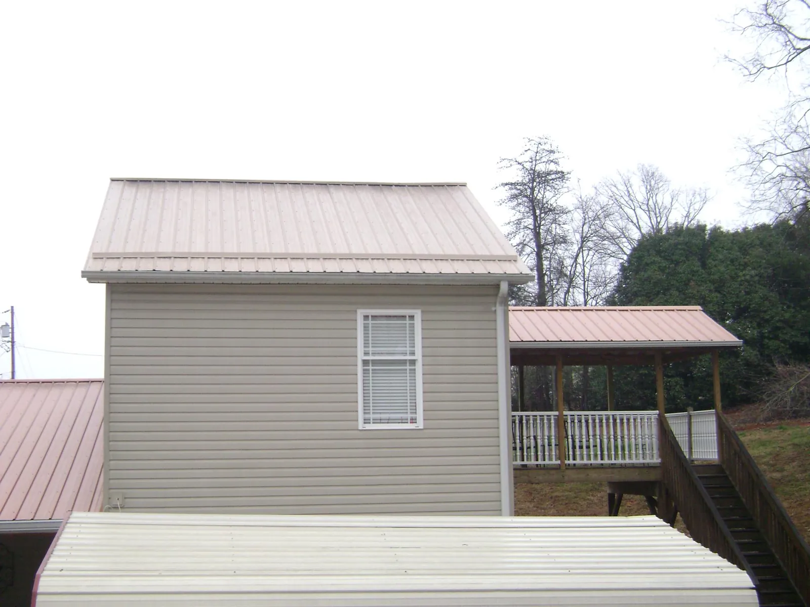 Tan metal roofs on a two story addition and attached porch, from a Roof Replacement job in Aguanga