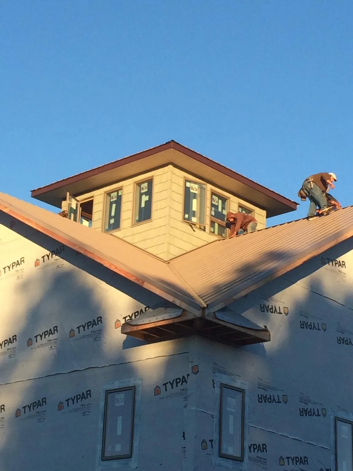 Roofers working around a rooftop cupola on a new metal roof at sunset — Roof Waterproofing in Aguanga by Roofing Brothers